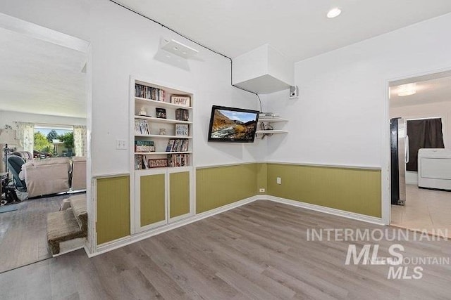 interior space with built in shelves, washer / dryer, wainscoting, and wood finished floors