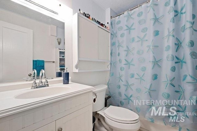 bathroom with toilet, curtained shower, vanity, and a textured ceiling