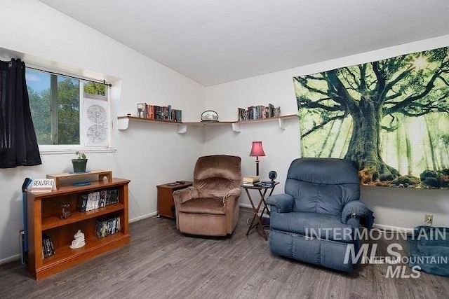 sitting room featuring baseboards, wood finished floors, and vaulted ceiling