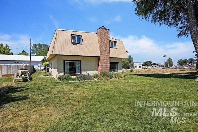 rear view of house featuring fence, metal roof, a lawn, and a chimney