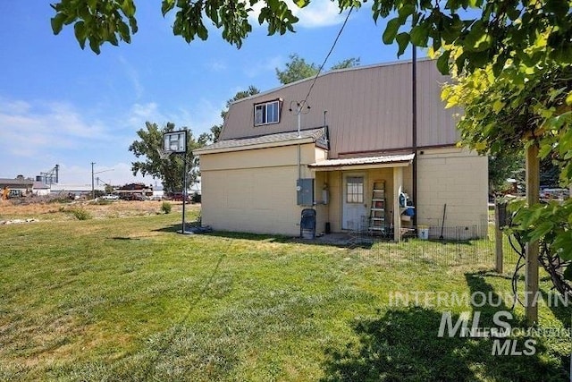 rear view of property featuring a yard, concrete block siding, and metal roof