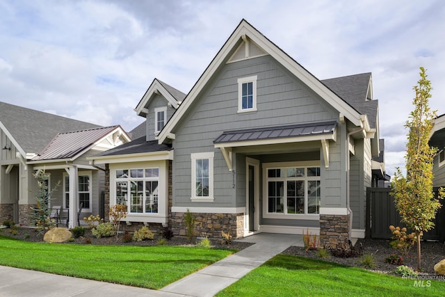 view of front of property featuring metal roof, stone siding, a front lawn, and a standing seam roof