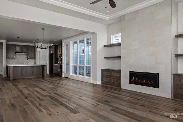 unfurnished living room featuring dark hardwood / wood-style flooring, a fireplace, and ceiling fan with notable chandelier