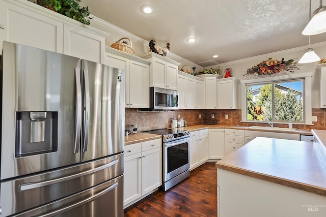 kitchen with white cabinetry, sink, hanging light fixtures, and appliances with stainless steel finishes