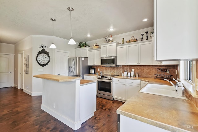 kitchen featuring white cabinetry, sink, a kitchen island, decorative light fixtures, and stainless steel appliances