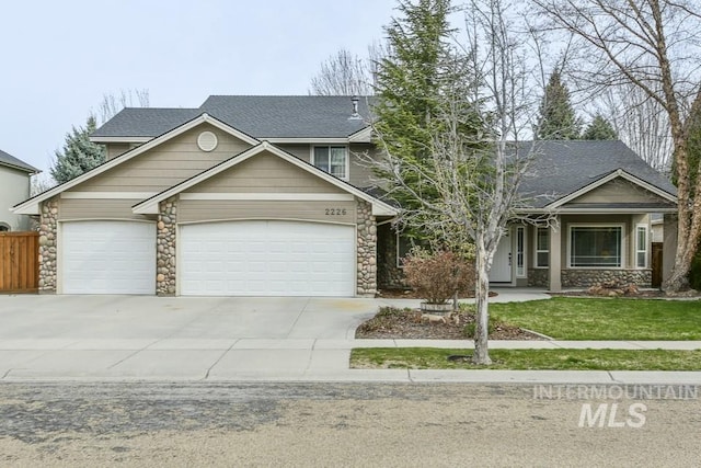 view of front facade with an attached garage, fence, driveway, stone siding, and a front yard