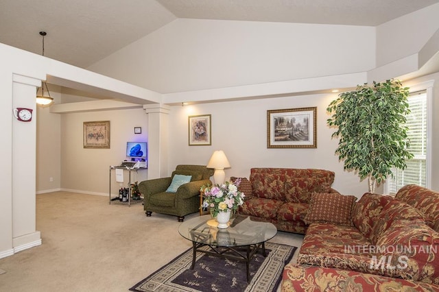 carpeted living room with decorative columns, high vaulted ceiling, and baseboards