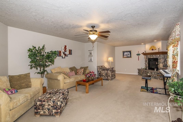 living room with a ceiling fan, carpet flooring, a stone fireplace, and a textured ceiling