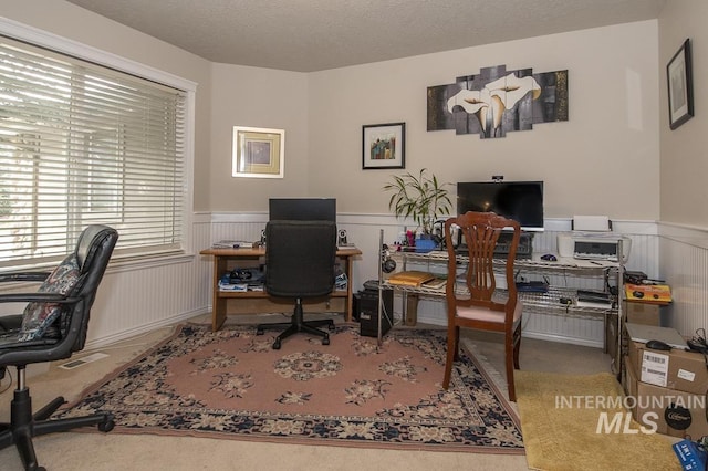 office space featuring a textured ceiling, wainscoting, and visible vents