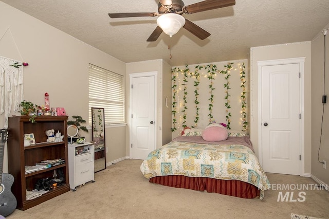 bedroom featuring light colored carpet, ceiling fan, a textured ceiling, and baseboards