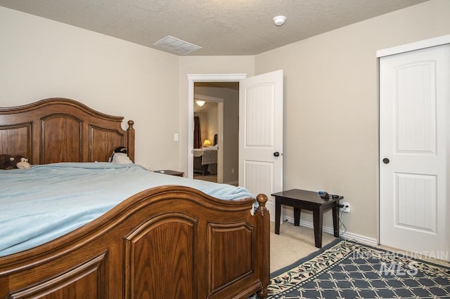 carpeted bedroom featuring a textured ceiling, a closet, visible vents, and baseboards