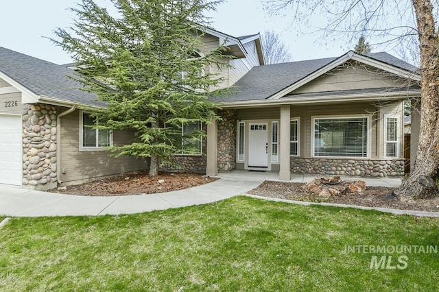 property entrance featuring a shingled roof, stone siding, and a yard