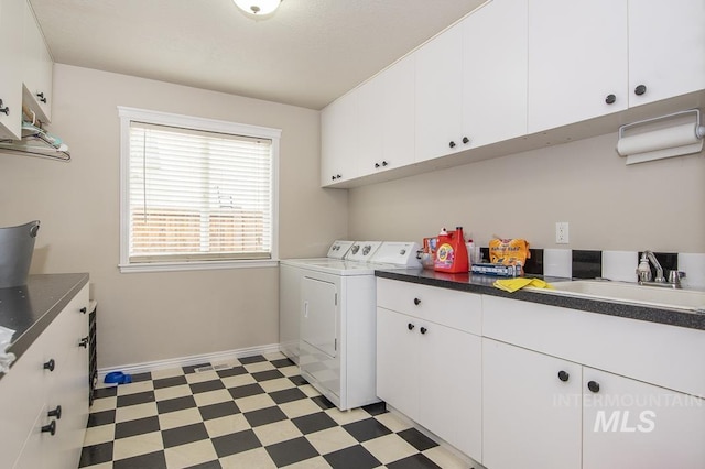 laundry room featuring washing machine and dryer, a sink, baseboards, cabinet space, and light floors