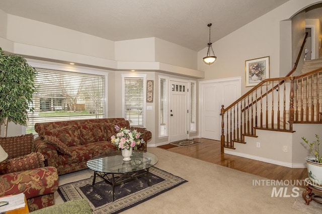 living room with high vaulted ceiling, wood finished floors, baseboards, and stairs