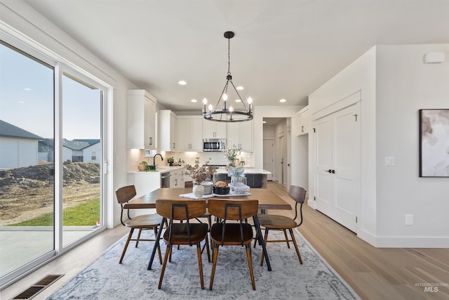 dining area with baseboards, visible vents, an inviting chandelier, light wood-type flooring, and recessed lighting