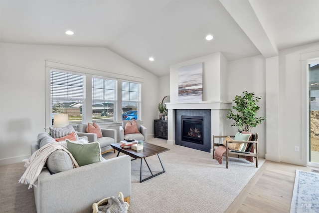 living area featuring lofted ceiling, baseboards, a glass covered fireplace, and recessed lighting