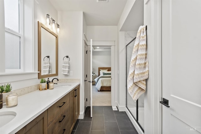 ensuite bathroom with ensuite bathroom, a stall shower, a sink, and tile patterned floors