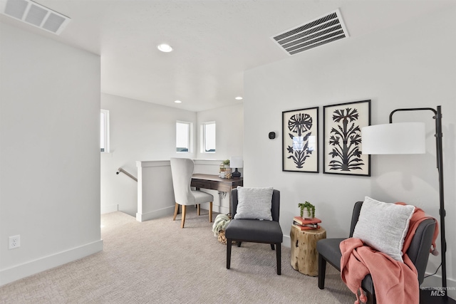 sitting room featuring carpet, visible vents, baseboards, and an upstairs landing