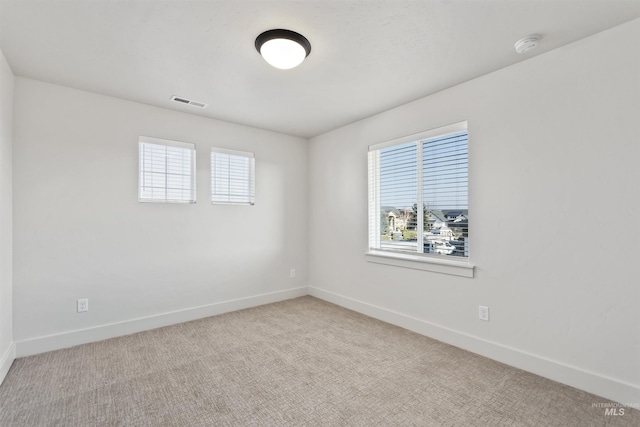 unfurnished room with carpet floors, visible vents, and baseboards