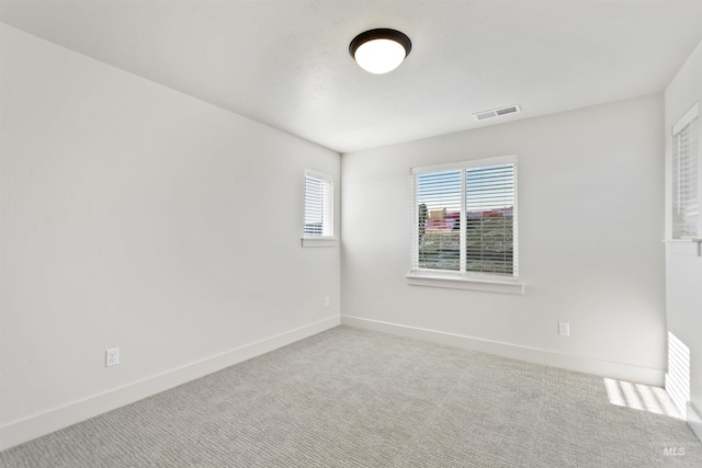 carpeted spare room featuring visible vents and baseboards