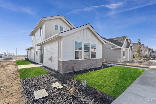 view of side of home featuring central AC, brick siding, board and batten siding, and a lawn