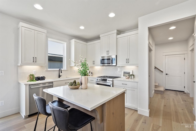 kitchen featuring light countertops, appliances with stainless steel finishes, a kitchen bar, and white cabinetry