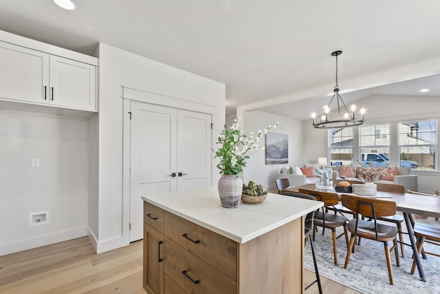 kitchen featuring light wood finished floors, open floor plan, vaulted ceiling, a kitchen island, and a chandelier