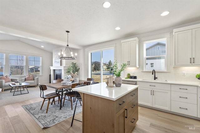 kitchen with a fireplace, a kitchen island, a sink, light wood-style floors, and open floor plan