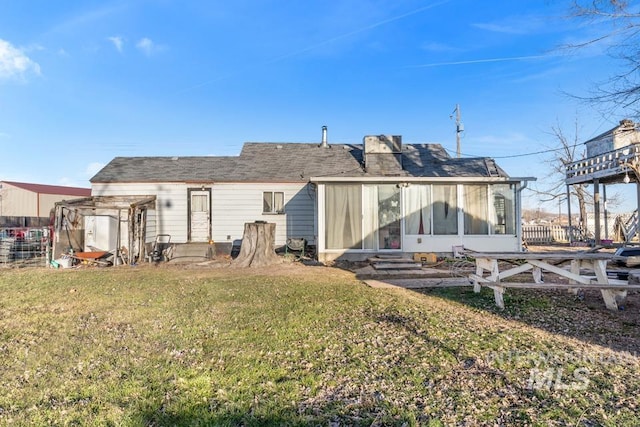 back of house featuring a pergola, a lawn, and a sunroom