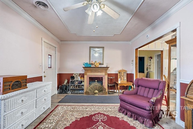 living area featuring crown molding, ceiling fan, and a fireplace