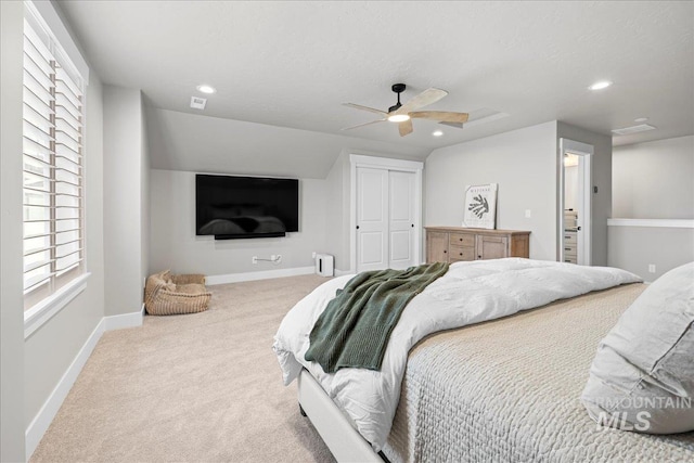 bedroom with ceiling fan, a closet, light carpet, and lofted ceiling