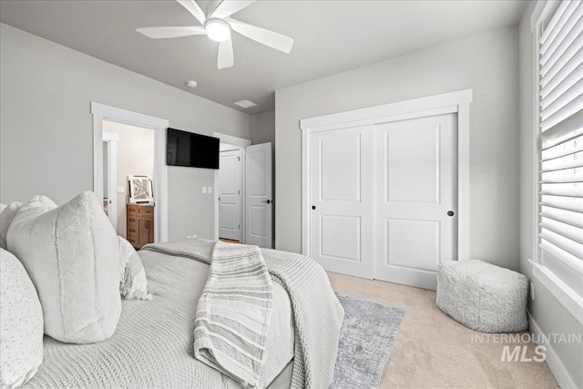 carpeted bedroom featuring ceiling fan, a closet, and ensuite bath