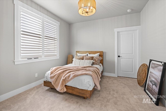 bedroom with light colored carpet and a chandelier