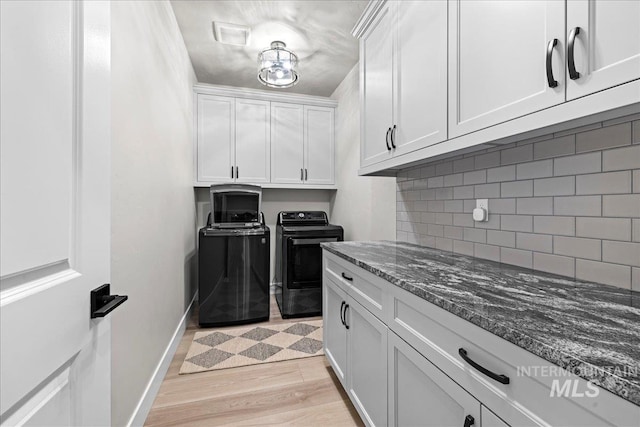 kitchen with separate washer and dryer, white cabinetry, dark stone counters, decorative backsplash, and light hardwood / wood-style flooring