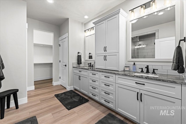 bathroom featuring hardwood / wood-style floors, walk in shower, tasteful backsplash, and vanity