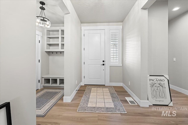 mudroom featuring light wood-type flooring, an inviting chandelier, and built in features