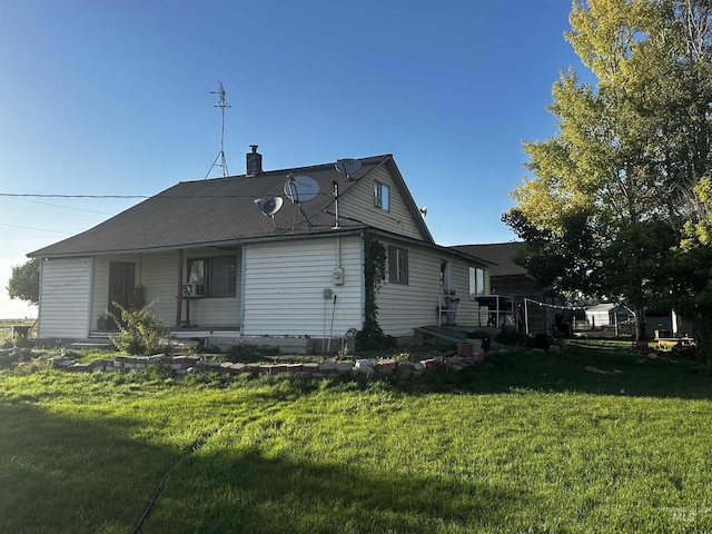 rear view of house with a chimney and a yard