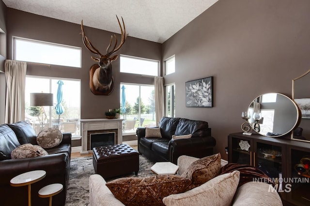 living room featuring baseboards, a fireplace, a textured ceiling, and a towering ceiling