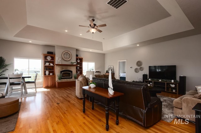 living area featuring a raised ceiling, visible vents, and a healthy amount of sunlight