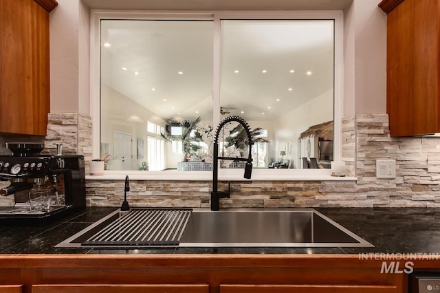 kitchen with dark countertops, brown cabinets, a sink, and decorative backsplash