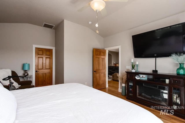 bedroom featuring lofted ceiling, wood finished floors, visible vents, and a ceiling fan