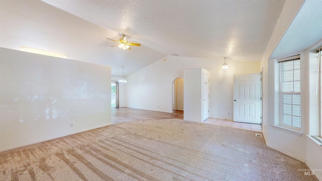 278 Trotter Dr, Twin Falls, ID 83301 - spare room featuring light carpet, vaulted ceiling, ceiling fan, arched walkways, and a textured ceiling
