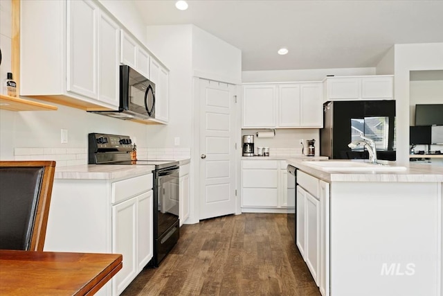 kitchen with black appliances, a sink, dark wood-type flooring, a kitchen island, and white cabinets