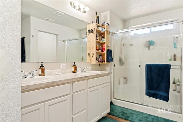 full bath with a shower stall and double vanity