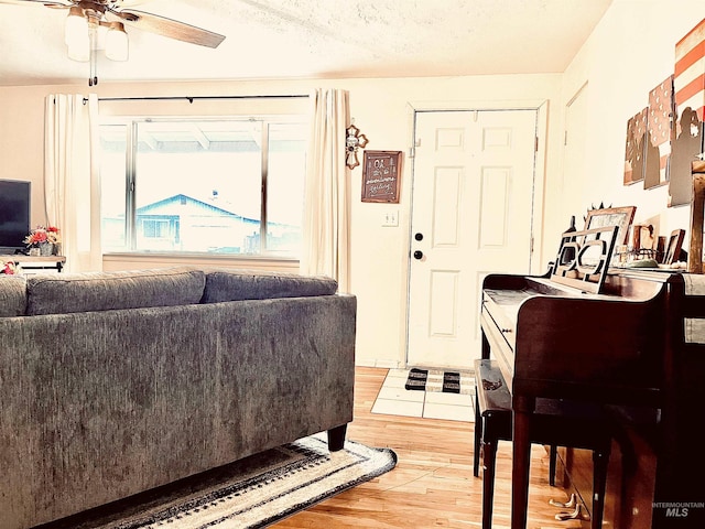 living room featuring a textured ceiling, wood-type flooring, and ceiling fan