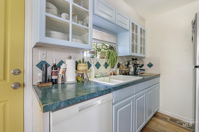 bar with white dishwasher, wood finished floors, a sink, baseboards, and tasteful backsplash