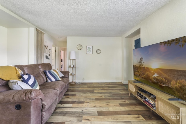 living area with a textured ceiling, baseboards, and wood finished floors