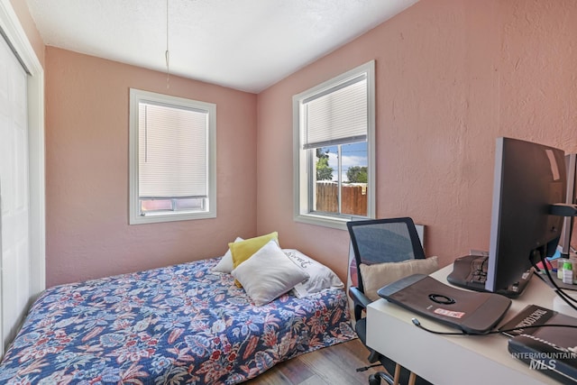 bedroom with a textured wall and wood finished floors