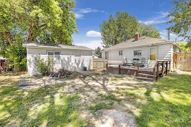 back of house featuring a chimney, a fenced backyard, a yard, and a deck