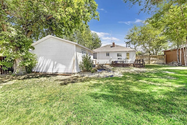 back of property with a yard, a deck, an outdoor structure, and fence